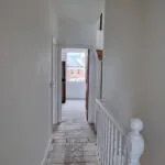 London builders and electricians renovating an interior hallway with stripped floorboards and freshly plastered walls