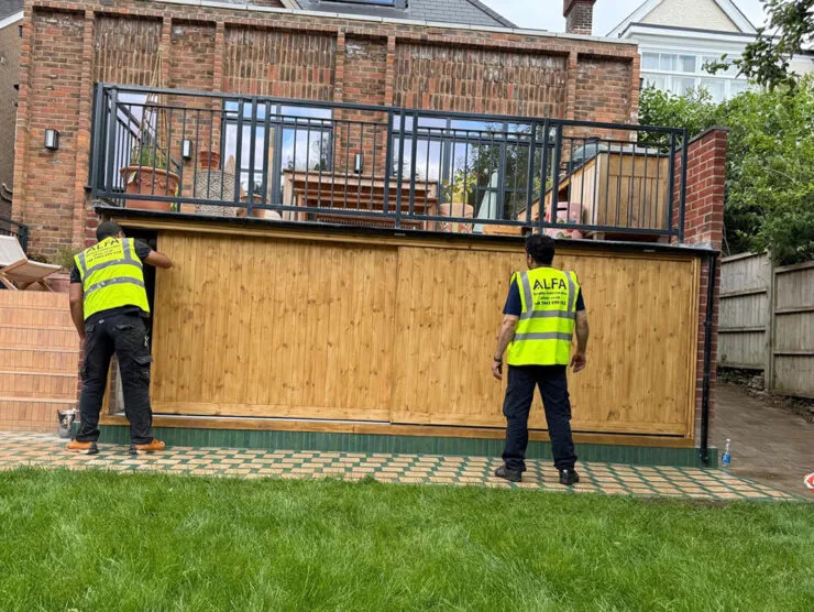 London builders and electricians installing a wooden garden gate during a home refurbishment.