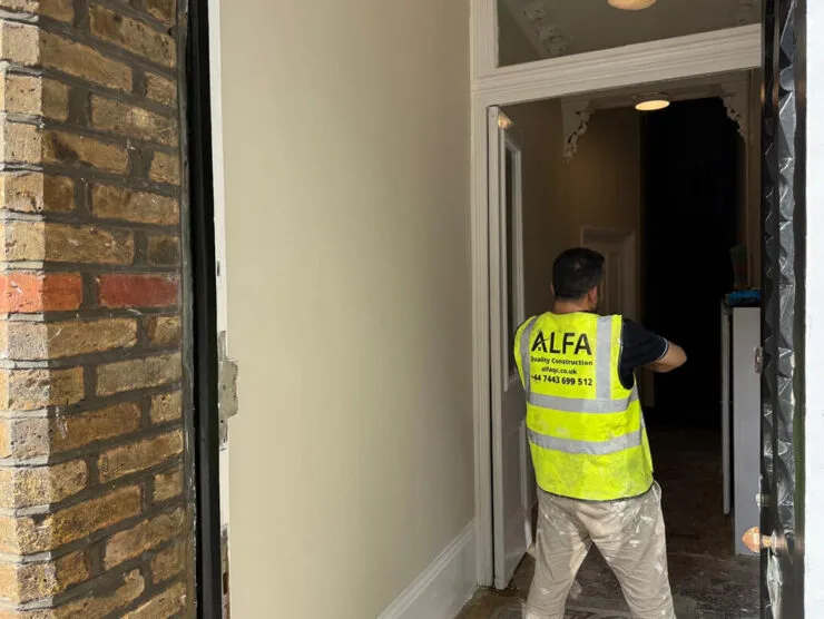 London builders and electricians working on a doorway refurbishment wearing an ALFA high‑visibility vest.